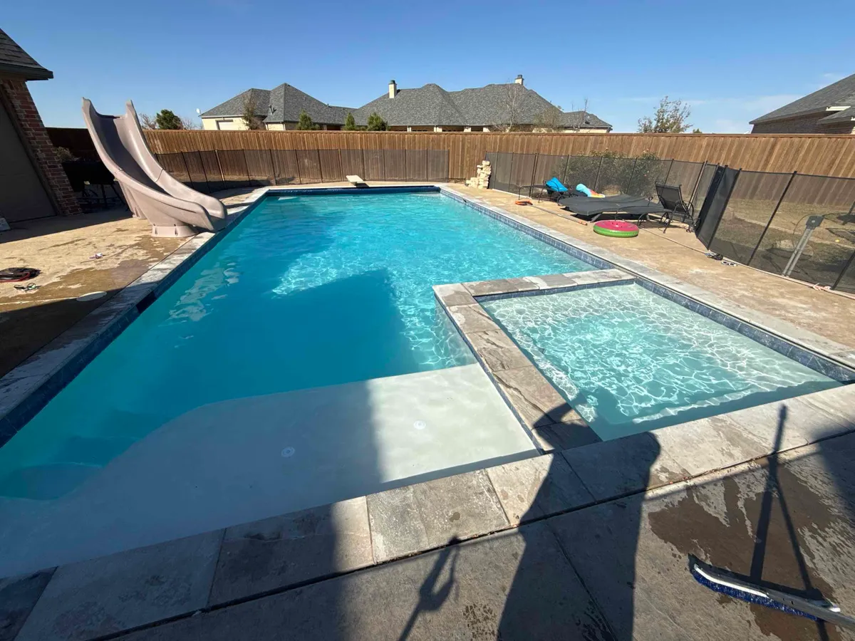 After: Rectangular backyard pool with an attached spa and stone coping