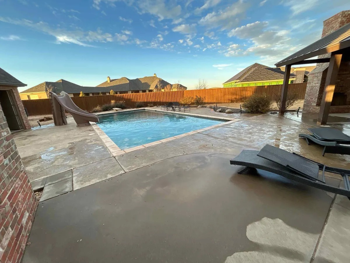 Before: Rectangular backyard pool with an attached spa and stone coping